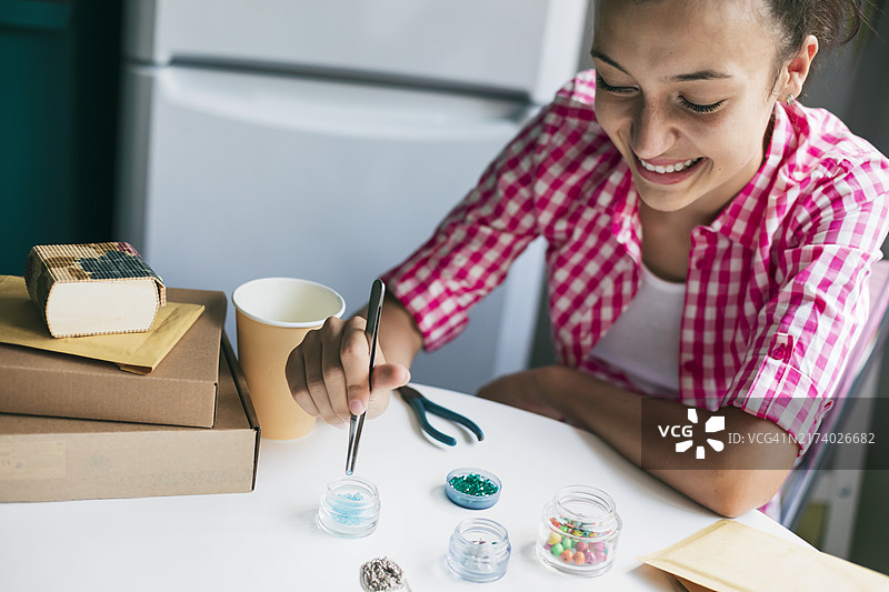 快乐的年轻女人制作手工珠宝图片素材