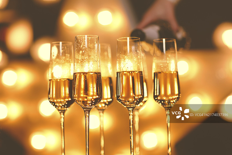 派对上明亮灯光模糊背景下的透明香槟酒杯图片素材