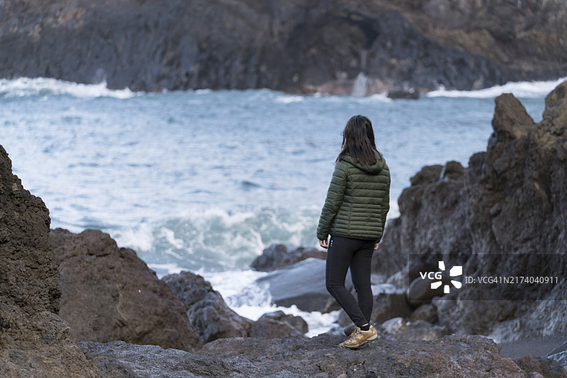 女人在马德拉塞萨尔的岩石海滩上观看海浪拍岸图片素材
