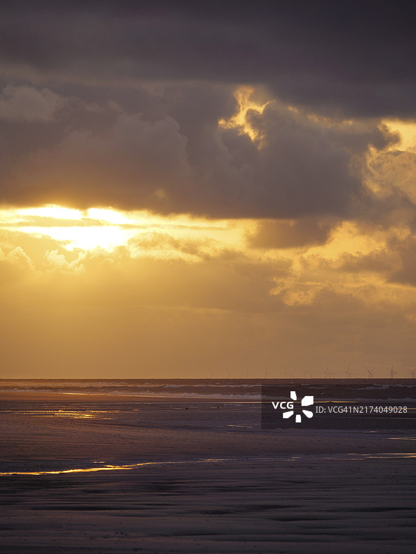 金色阳光穿透浓密的云层，照耀着北海安静的海滩图片素材