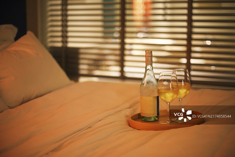 床上两杯白葡萄酒，背景虚化，留白图片素材