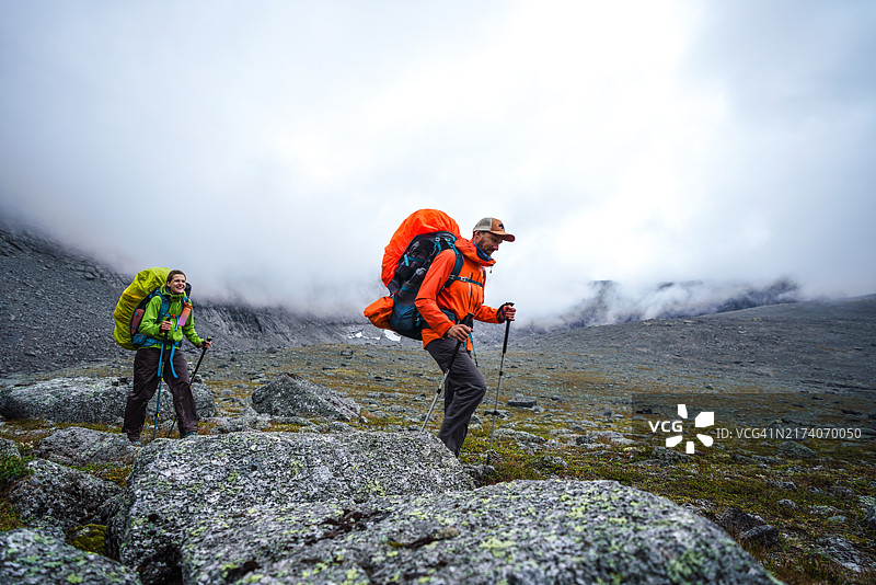两名徒步者背着背包在多云的山中，暴风雨即将来临。科拉半岛希比内山图片素材