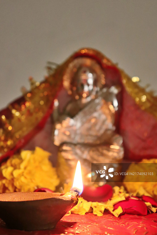 萨拉斯瓦蒂女神像与彩绘花布、点燃的泥土油灯、万寿菊和玫瑰花/九夜节图片素材