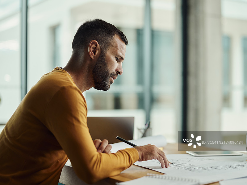 男建筑师在办公室分析蓝图图片素材