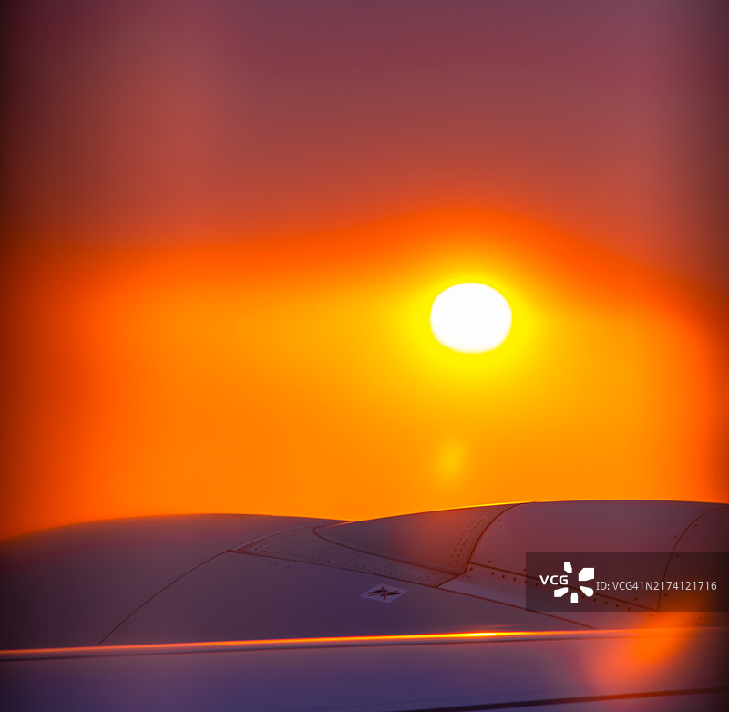 飞机舷窗视角：云层之上的美丽日落图片素材