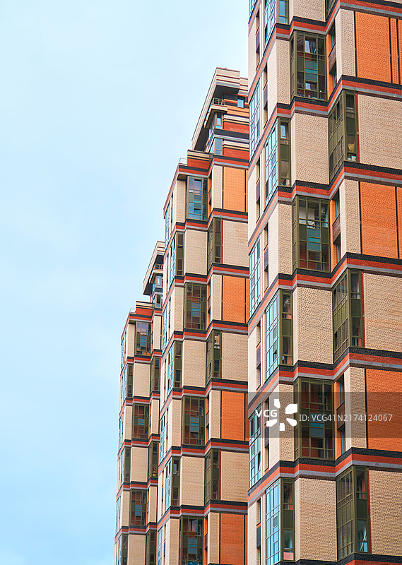 在晴朗的蓝天下，具有独特建筑设计的城市现代住宅楼，带有复制空间图片素材