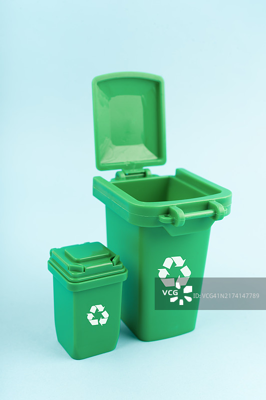 蓝色背景上的带回收标志的绿色垃圾箱图片素材