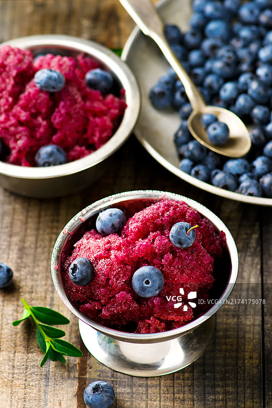 金属花瓶中的越橘冰沙和碗中的新鲜蓝莓图片素材
