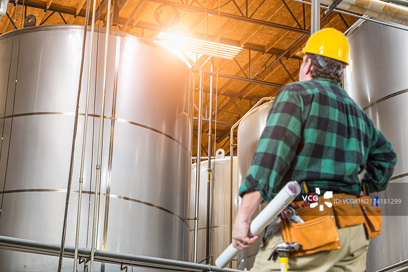 戴着安全帽的男人抬头看着大型工业储罐图片素材