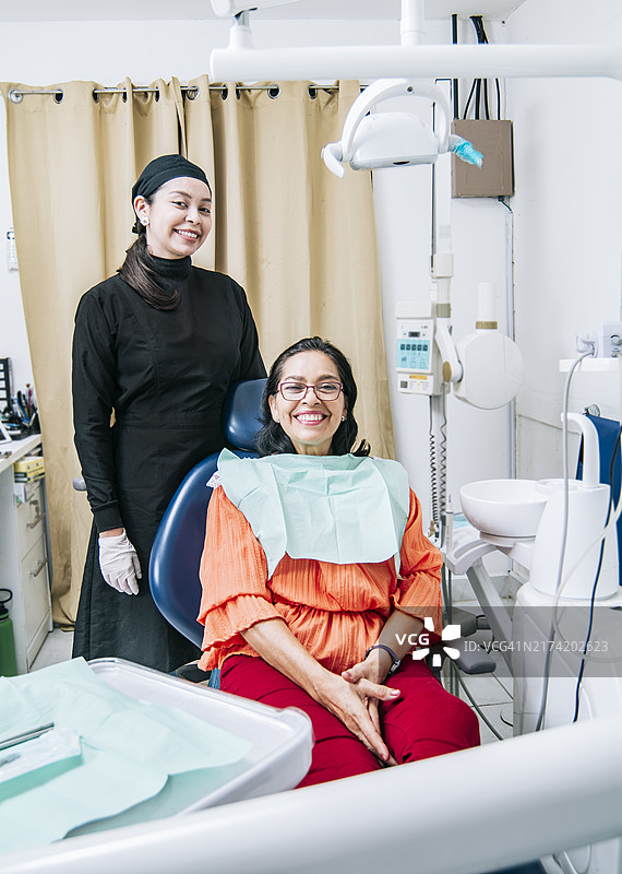 牙医和微笑的病人看着镜头，牙医和病人概念图片素材