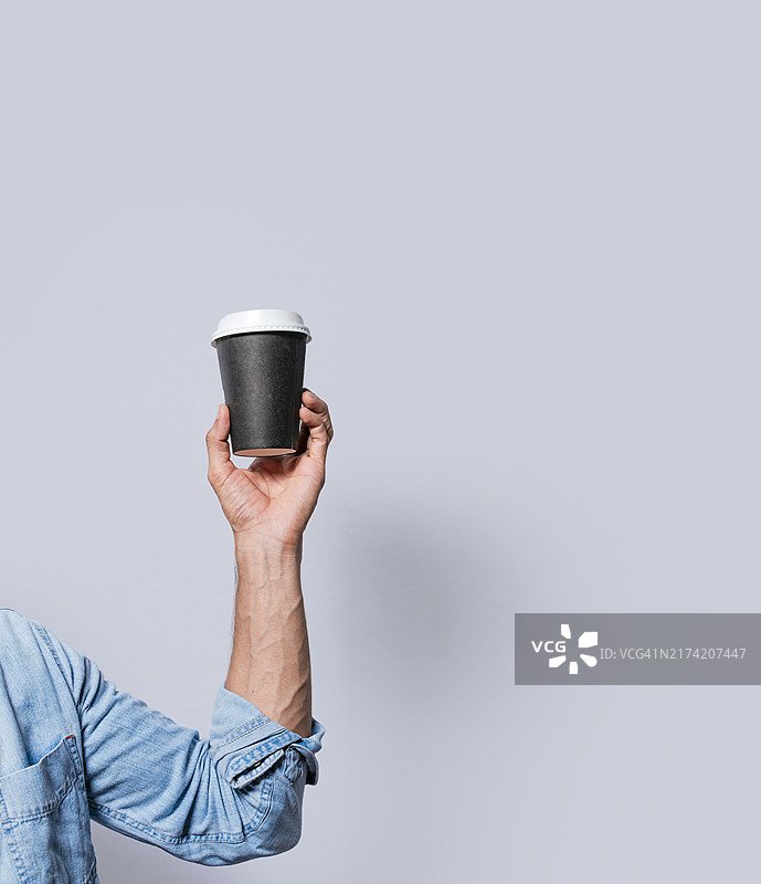 手持纸杯咖啡的特写。手持外带咖啡，手臂拿着咖啡杯图片素材