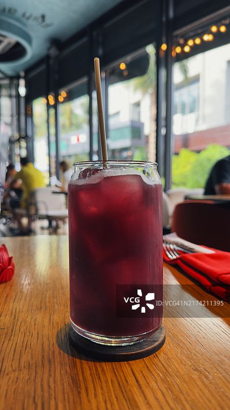 现代咖啡馆木桌上的冰镇紫色饮品图片素材