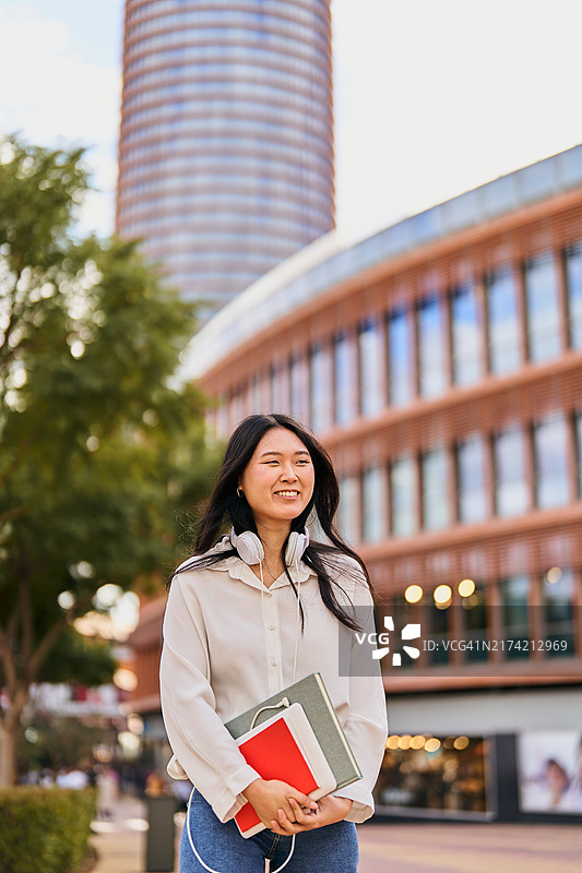 走在校园里拿着书和平板电脑的学生图片素材