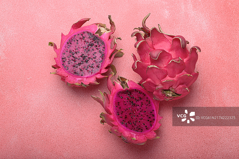 粉色背景上的三块火龙果切半图片素材