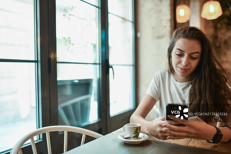 在酒吧喝咖啡玩手机的可爱女人图片素材
