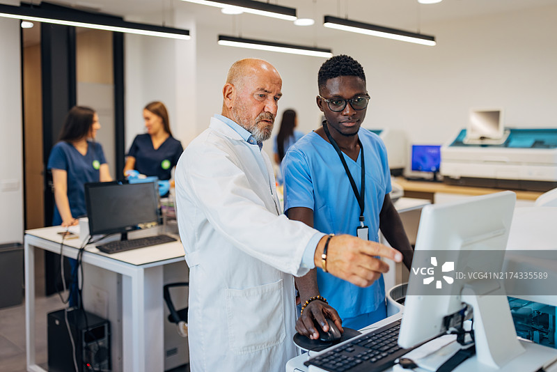 男学生认真听取资深科学家讲解医学样本的实验室测试方法图片素材