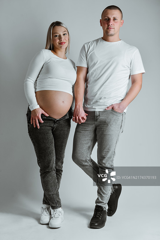 准父母在影棚里拍摄孕妇照，手牵着手图片素材