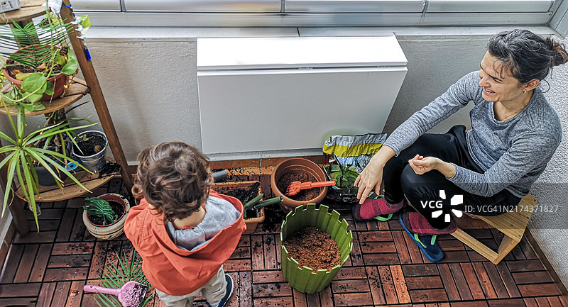 孩子和母亲在木制露台上种植花园图片素材