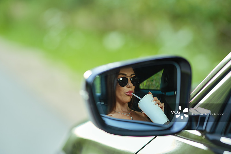 汽车后视镜中女人喝饮料的倒影图片素材