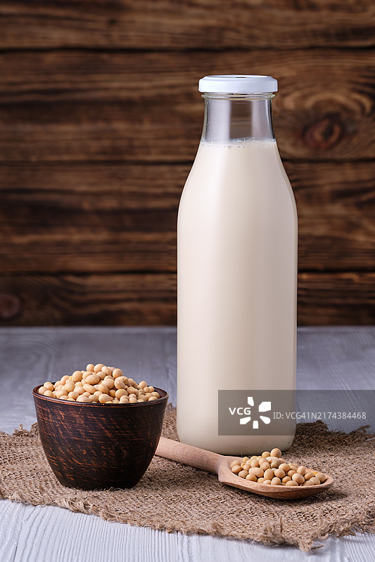 封闭的豆奶瓶，配小碗、勺子和大豆图片素材