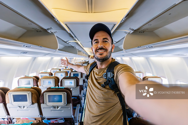 快乐的男乘客在飞行前在飞机上用手机自拍图片素材