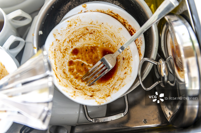 水槽里的脏盘子，堆积如山的餐具和盘子正在冲洗图片素材