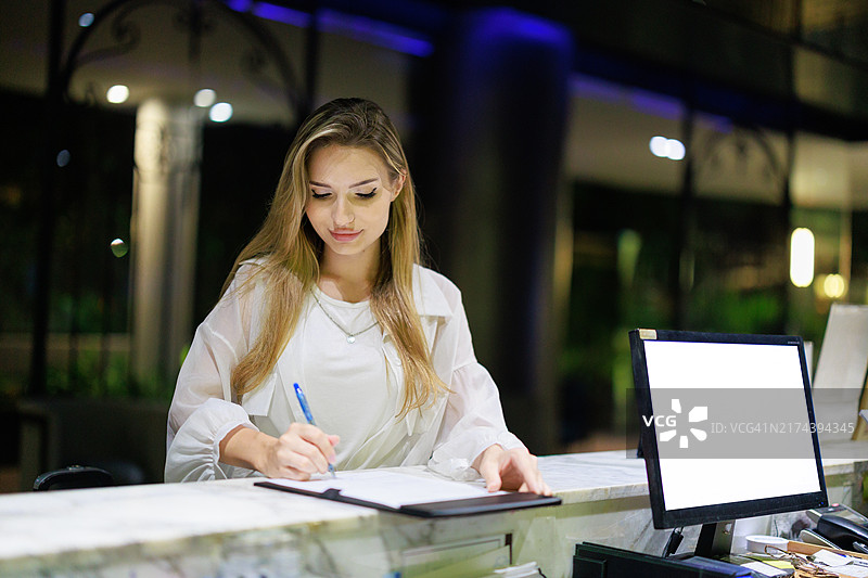 酒店前台接待服务:白人女旅客在前台办理入住;旅行和旅游;商务旅行;酒店工作人员与客人互动;豪华酒店的温馨氛围图片素材