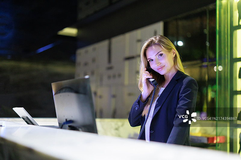 在现代酒店大堂打电话的商务白人酒店经理；自信的女商人正在前台进行客户沟通和客户服务。图片素材