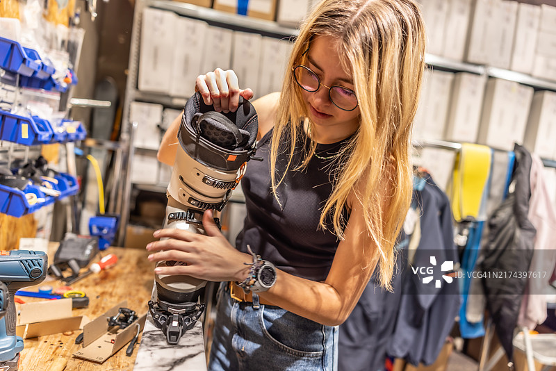 一位年轻的熟练维修技师为新的冬季准备高山滑雪板图片素材