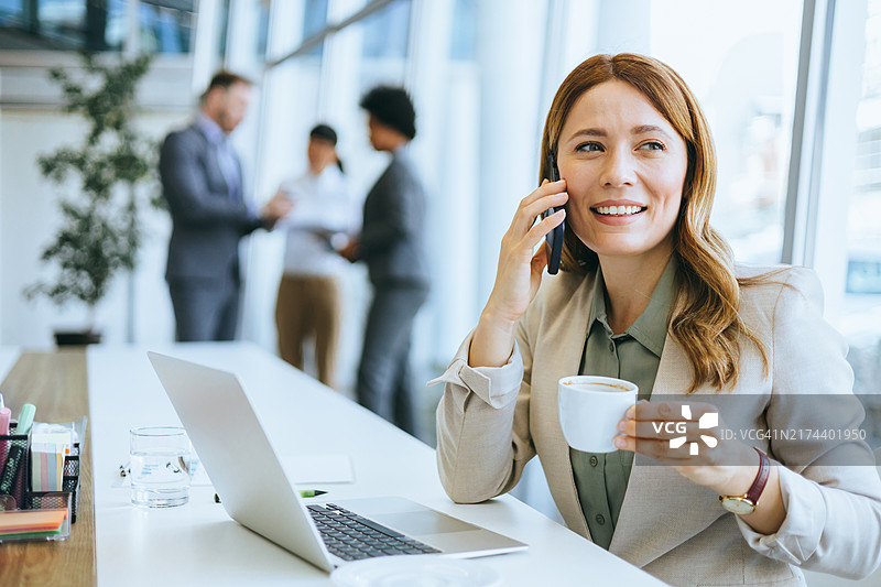 打电话 holding 咖啡杯的微笑女人图片素材