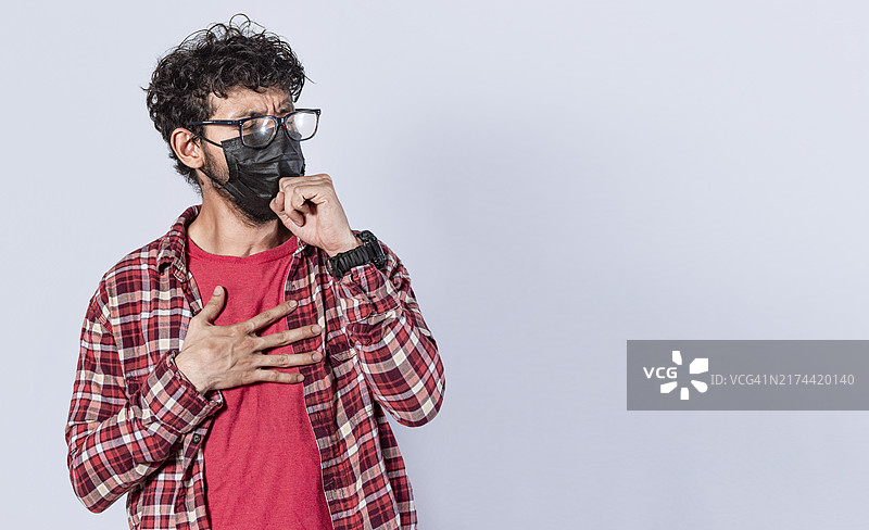 戴着口罩咳嗽的男人，关于冠状病毒爆发、社交疏远和呼吸系统问题的概念图片素材