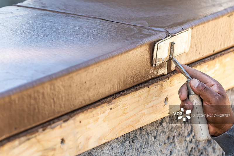 建筑工人在潮湿水泥上使用手动开槽器，形成新泳池的镶边图片素材