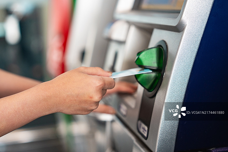 一位年轻女士在大都市使用自动取款机特写：取款、支付、查询余额和转账图片素材
