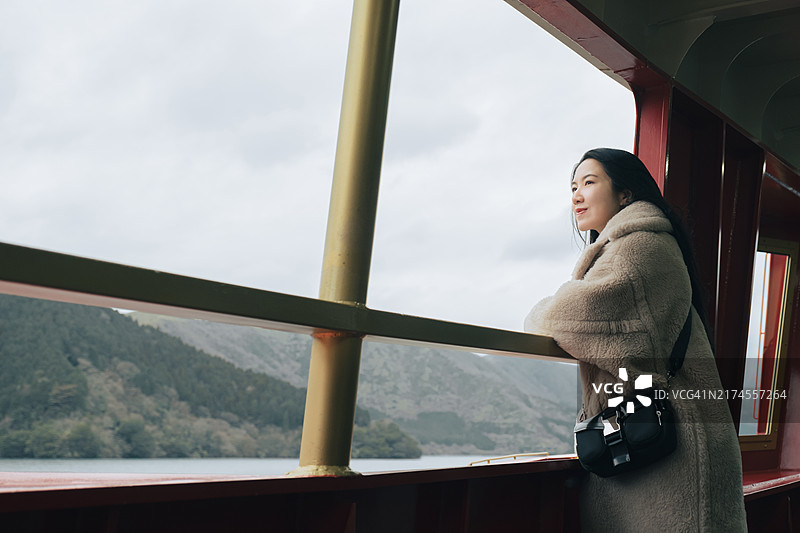 亚洲女性游客在观光船上欣赏河口湖的美景。图片素材