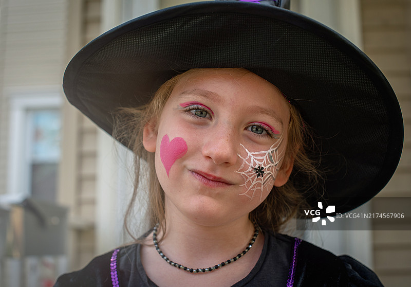 变戏法过万圣节，5岁女孩的女巫服装和节日彩绘闪耀着兴奋的光芒图片素材