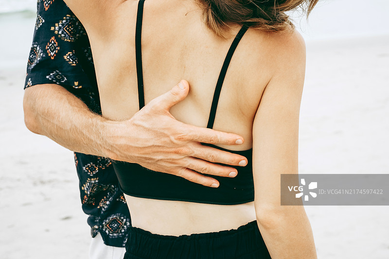 沙滩上温柔的拥抱，展现了两人之间充满爱意的温馨时刻图片素材