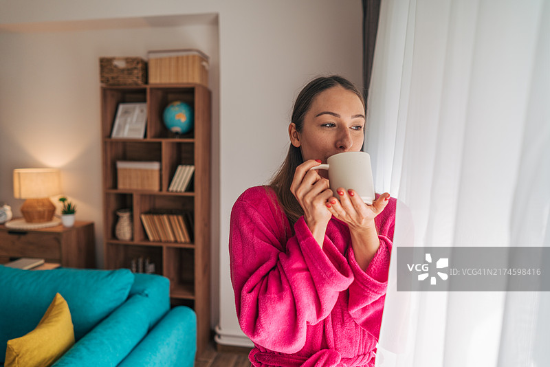 年轻女子在客厅窗边身穿浴袍图片素材