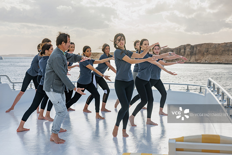 老年教练在船上甲板上教授年轻女性太极课程图片素材