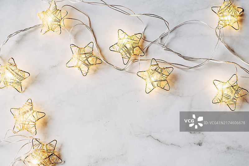 抽象背景中冷杉树枝上悬挂的圣诞星灯串图片素材