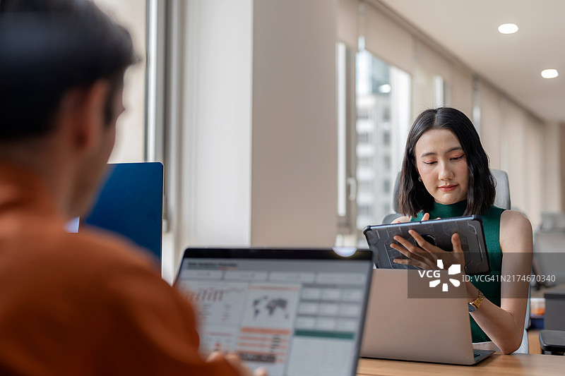 多元化的业务团队利用数据分析来预测现代办公室战略会议期间的市场趋势。团队成员协同工作，使用笔记本电脑和数字显示器分析影响业务成功的关键因素图片素材