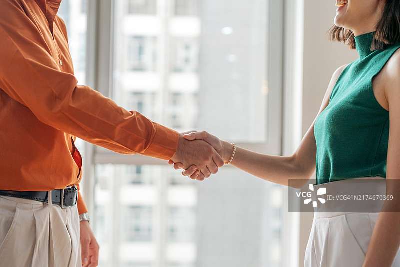 女商人与同事握手的特写，象征着专业环境中的成功合作和团队合作。这个有力的姿态反映了工作场所中的团结、合作和互信。图片素材