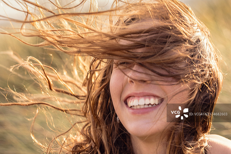 笑得很开心的美丽少女面部特写，头发被风吹散图片素材