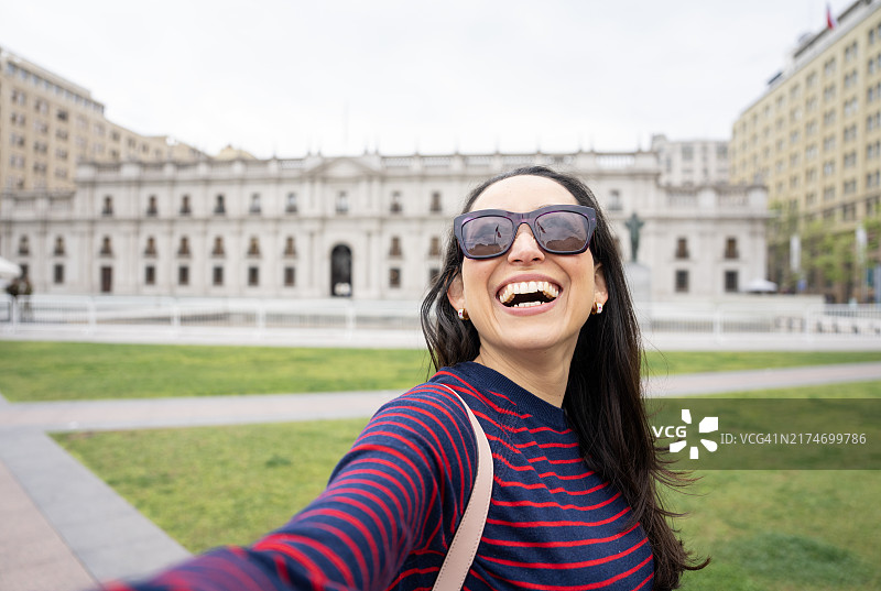 快乐的年轻游客在智利圣地亚哥的货币宫前自拍图片素材