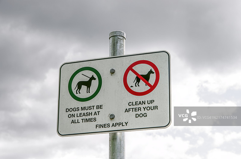 公园警告标志：狗必须随时系上皮带，清理狗的粪便，违者罚款图片素材