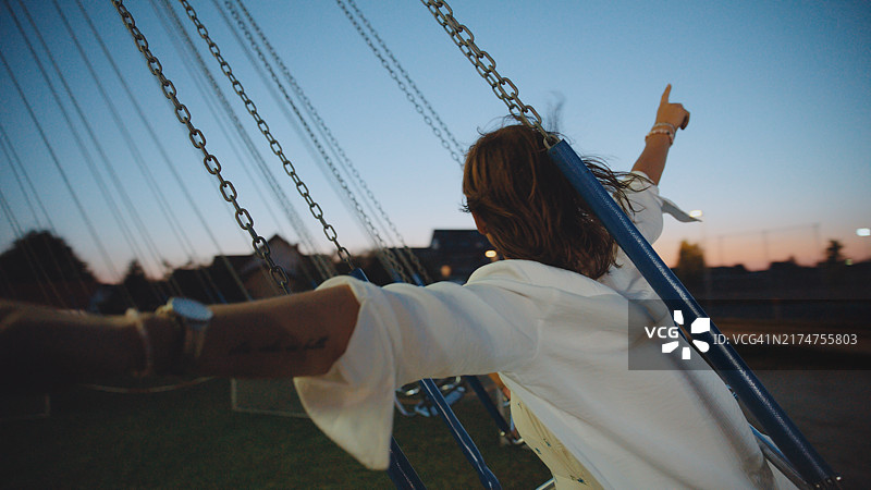 在夜市旋转木马上玩耍的快乐白人女性图片素材