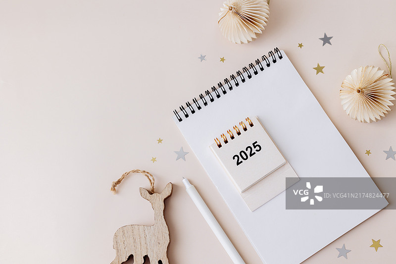 新年计划概念：米色桌子上的空白笔记本、笔和圣诞装饰品。圣诞节、新年快乐、决心、目标、待办事项列表、战略和计划概念。具有复制空间的平面图图片素材