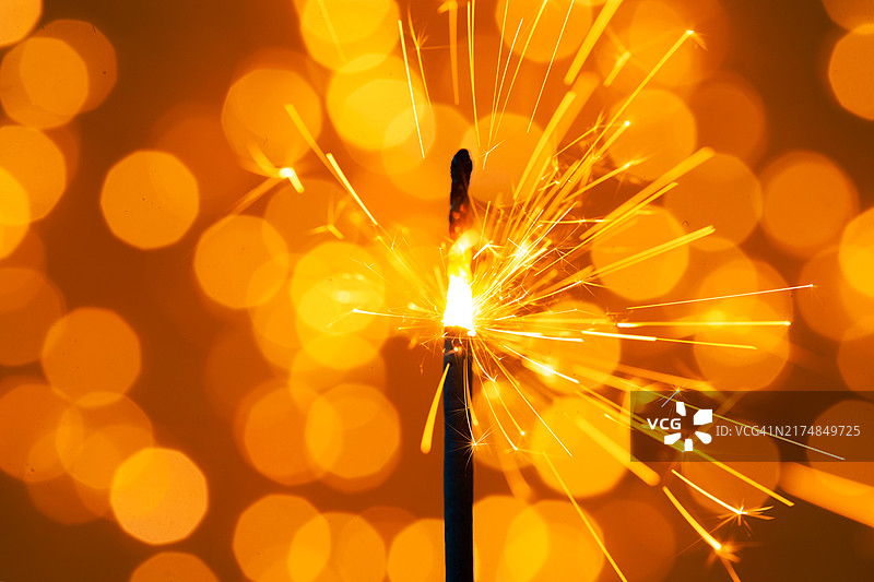 明亮背景上带有金色节日散景的燃烧烟花，新年或生日庆祝概念，微距摄影图片素材