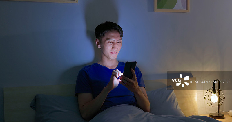 男人滑动智能手机在黑暗中图片素材