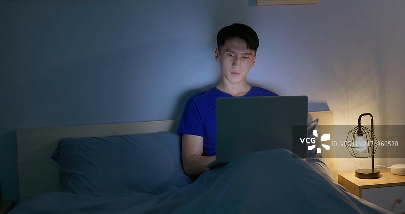 男人在床上使用笔记本电脑图片素材
