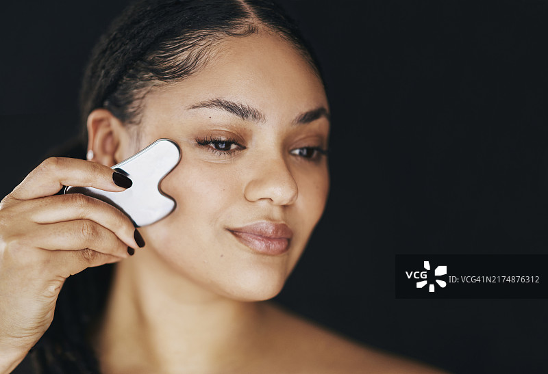 女人在护肤程序中使用刮痧板图片素材